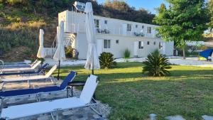 a group of chairs and umbrellas in front of a house at Greco Paradise Suites - ADULT ONLY in Nea Skioni