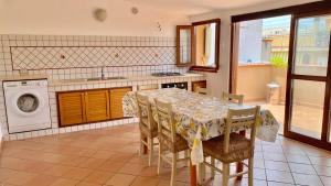 uma cozinha com uma mesa com cadeiras e uma máquina de lavar roupa em Casa Giusy em Terrasini