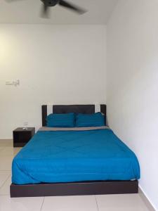 a bed with a blue comforter and two blue pillows at Homestay Desaru Utama @Escadia in Bandar Penawar