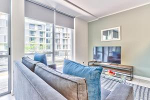 a living room with blue chairs and a couch at Harbour Bridge Waterfront in Cape Town