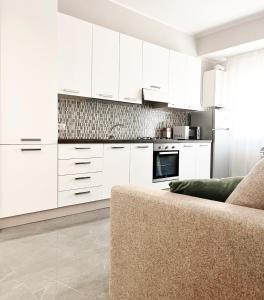 a white kitchen with white cabinets and a couch at Casa Grande in Crotone