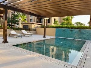 una piscina con 2 sillas junto a un edificio en New 2 bedroom entire apartment in Madinat Jumeirah Living, en Dubái