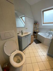 La salle de bains est pourvue de toilettes, d'un lavabo et d'une baignoire. dans l'établissement Maison de vacances moderne et spacieuse situé à 20 minutes de BXL, Antwerp & Gent, à Merchtem