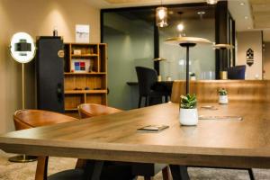 a large wooden table in a room with chairs at Best Western Plus Le Conquerant Rouen Nord in Bois-Guillaume