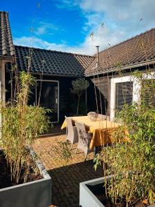 un patio con mesa de madera y sillas frente a una casa en De Appelhoeve en Terschuur
