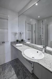 Baño blanco con lavabo y espejo en Hotel Soho, en Landau in der Pfalz