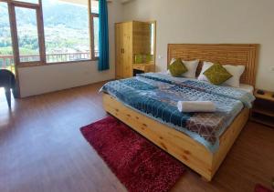um quarto com uma cama grande e uma janela grande em Bodh Holiday Homes by StayApart em Manali