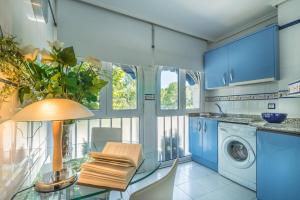 a kitchen with blue cabinets and a glass table with a lamp at Apartamentos Las Brisas in Santander