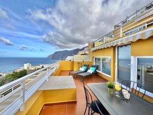 Un balcón con mesa y sillas y el mar. en Mirador de Los Gigantes, en Puerto de Santiago