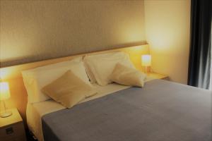een slaapkamer met een bed met kussens en 2 lampen bij BeBIGEA Siracusa in Siracusa