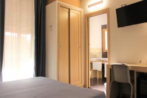 a bedroom with a bed and a desk and a television at BeBIGEA Siracusa in Siracusa