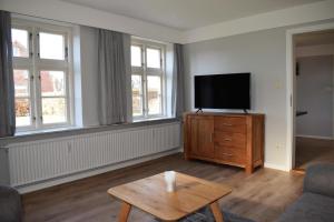 a living room with a flat screen tv on a wooden dresser at Haus Amsel in Niebüll