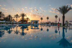 a pool with palm trees and a sunset in the background at Mirage Park Resort-Ultra All Incl. in Kemer