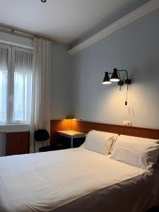 1 dormitorio con 1 cama blanca grande y escritorio en Hostal La Vera, en Madrid