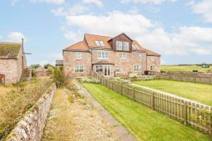 a large brick house with a fence and a yard at The Cottage, Craighead Farmhouse in Crail