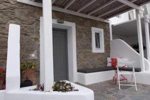 a porch with a door and a table and a chair at Bellou Suites in Mýkonos City