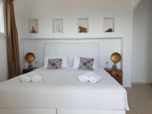 a bedroom with a white bed with towels on it at Bellou Suites in Mikonos