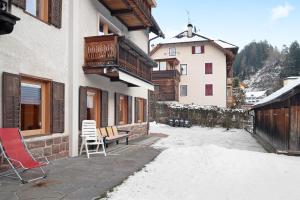 a building with a bench and chairs in the snow at Appartamento Cesa Wanker in Ortisei