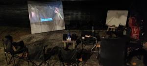 a group of people sitting in chairs in front of a screen at Teniat Village in Rantau Panjang
