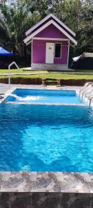a swimming pool with a purple house in the background at Teniat Village in Rantau Panjang
