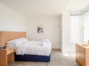 een witte slaapkamer met een bed en een bureau bij 1 Bed in Bude 78616 in Bude
