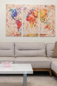 four paintings of a world map on a wall above a couch at Bright home SKG in Thessaloniki