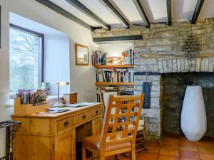a wooden desk with a chair in a room with a stone wall at 5 Bed in Crickhowell BN365 in Llangattock