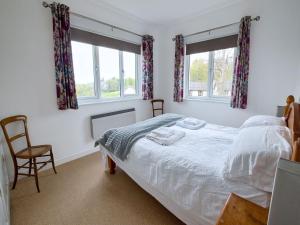 a bedroom with a bed and a chair and two windows at 3 Bed in Narberth FB138 in Narberth
