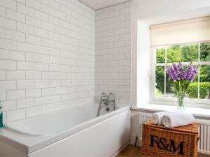 a white bathroom with a tub and flowers in a window at 4 Bed in Hay-on-Wye Town BN116 in Hay-on-Wye