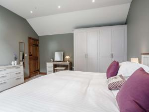 1 bed in Harrogate 83317 في Shaw Mills: غرفة نوم مع سرير أبيض كبير مع وسائد أرجوانية