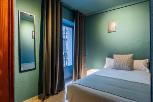 1 dormitorio con cama, espejo y ventana en Ideal Hostel Madrid, en Madrid