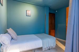 1 dormitorio con 1 cama con pared azul en Ideal Hostel Madrid, en Madrid