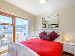 a bedroom with a red bed and a large window at 1 Bed in Arrochar 82648 in Arrochar