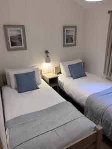 a bedroom with two beds with blue pillows at Ellesmere Lodge in Morenish