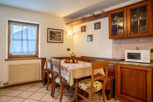 cocina con mesa con sillas y microondas en Casa al portico Val di Cembra en Grauno