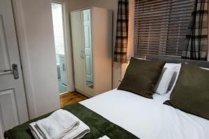 a bedroom with a bed with white sheets and green pillows at Stylish 3 bedroom flat, free parking in London