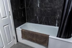a bathroom with a white bath tub with a black wall at Stylish 3 bedroom flat, free parking in London