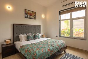 Un dormitorio con una cama grande y una ventana en StayVista's Aranyavas Farmstay - Pet-Friendly, Mountain-View Retreat with Terrace, Lawn & Indoor-Outdoor Games, en Jaipur