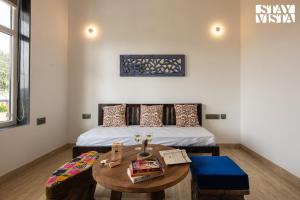 Habitación con cama, mesa y sidra de mesa en StayVista's Aranyavas Farmstay - Pet-Friendly, Mountain-View Retreat with Terrace, Lawn & Indoor-Outdoor Games, en Jaipur