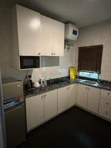 una pequeña cocina con armarios blancos y microondas en Zucchini Hotel and apartments, en Umueme