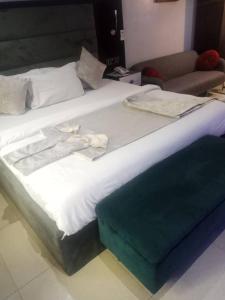 un grande letto con lenzuola bianche e asciugamani sopra di Zucchini Hotel and apartments a Umueme