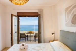 a bedroom with a bed and a view of the ocean at Irida beachfront Villa for 12 steps to amenities in Rethymno