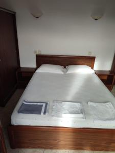 a bed with a wooden frame and white sheets at Ξενώνας Φωτεινη in Ouranoupoli