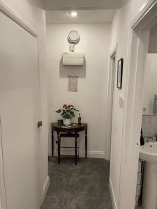 een badkamer met een wastafel en een tafel met bloemen bij Lovely 1 bedroom flat in quiet Wimbledon in Londen