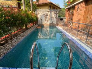 a swimming pool with stairs leading to a house at Raichak 3BHK 28ft pool Villa in Raichak