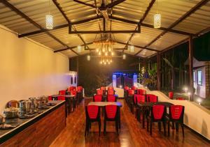 a restaurant with red chairs and tables in a room at Areca Jungle Stays by StayApart in Potolai