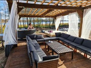 a patio with couches and a table and a tub at Poilsiaviete Vakaris in Gudeliai