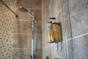 a soap dispenser on the wall of a shower at The Nest, lovely apartment in Holt