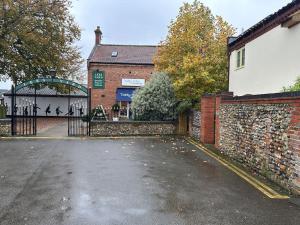 an empty parking lot in front of a building with a gate at The Nest, lovely apartment in Holt