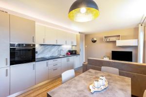 a kitchen with white cabinets and a table with chairs at La Sorgente Ville di Fiemme in Carano +15 photos
